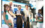 レースクイーンと一緒に写真撮影に応じるインテル株式会社代表取締役共同社長の吉田和正氏、ロビー・スウィヌン氏、九十九電機社長の鈴木淳一氏の画像