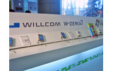 ウイルコムの体験コーナー。本日発売のW-OAM対応超小型通信モジュール「W-SIM」も展示されている。その他、NTTドコモとソフトバンクモバイルもそれぞれ体験コーナーを設け、担当スタッフが説明にあたるの画像