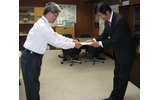 高崎一郎 総務省 四国総合通信局長（左）から免許状を受領する片岡浩一 UQコミュニケーションズ 副社長（右）の画像