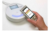「かざすクーポン」を保存した携帯電話とレジ横のリーダーライターの画像