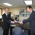村上晃 総務省 北海道総合通信局無線通信部長（左）から免許状を受領する片岡浩一 UQコミュニケーションズ 副社長（右）