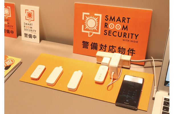 月々500円（税別）で留守中の不正な侵入を検知することができる「SMART ROOM SECURITY」の基本セット。左から、リモコン、マグネットセンサー2個、親機（コンセントに挿されているもの）（撮影：防犯システム取材班）