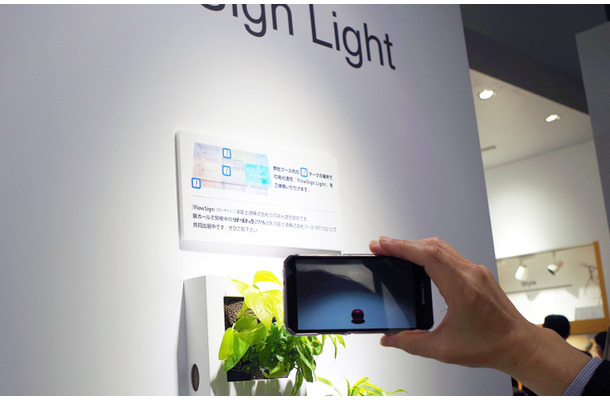 三菱側の展示ではそれぞれの照明で別々のコンテンツを表示させていた。室内の一般的な照明とは別に、指向性のあるLED照明の周りでスマートフォンをかざすことでコンテンツを表示する（撮影：防犯システム取材班）