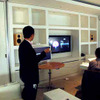 本社で行われた記者会見でのデモ風景。Apple TVをリモコンで操作しているの画像