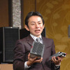 新開発の電源ユニットを見せる山中氏。向かって右の小さい方がが新しい100V電源の画像