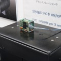 光学防振機構を搭載した超小型カメラモジュール「MP1010M-VC」を使ったデモの様子。黒い台は常に微振動を繰り返している（撮影：防犯システム取材班）