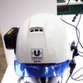 「Uメイト」をヘルメットに装着したところ。ヘッドセットもあるのでハンズフリーで作業に専念できる（撮影：防犯システム取材班）