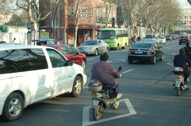 高級車や電気バイクが行きかう。信号が機能していない場合が多く、人々はタイミングを見計らって道を横断する