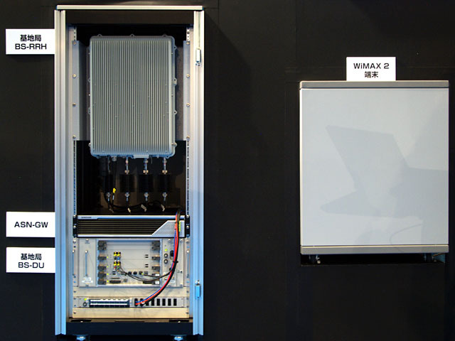 左の「BS-DU」（信号処理・制御など）と「BS-RRH」（無線部）が基地局設備で、従量はそれぞれ約20kg程度。端末は現在FPGAボードで実現しており、右のキャビネットの中に収められている