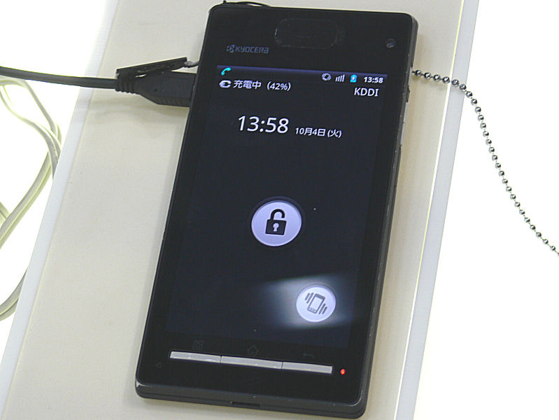 新聴覚スマートフォンのデモ機は既存製品の筐体をそのまま利用。カナルタイプ（耳栓型）のイヤホンで音楽聴いている最中でも、実機を耳に当てれば電話の音声が聞こえる。