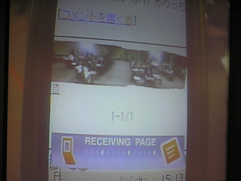 会見場の記者席のパノラマ画像を表示している携帯端末の画面。画面ではやや見づらいが、記者数などがわかる