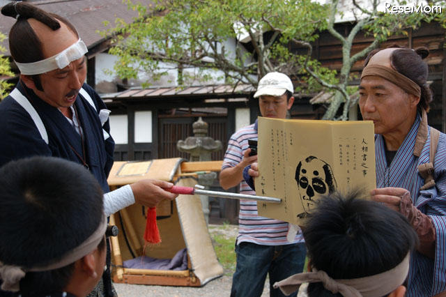 「こいつが下手人だ」と頭が示すのは、当時の書き方をそのまま模した「手配書」