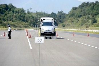 「50％転がり抵抗低減タイヤ」のテスト走行の模様。テスト車はプリウスで、積載車に搭載されたあと、ギアをニュートラルに入れて惰性で走りだす。「50％転がり抵抗低減タイヤ」で121.6m、同条件でA-cクラスが83.9mと、1.5倍近くの違いになった例もあった。