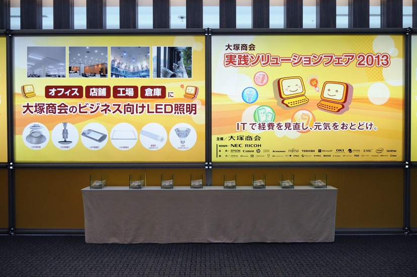 会場の入り口に設置された看板。ITで経費を見直し、元気をお届け。」というテーマ