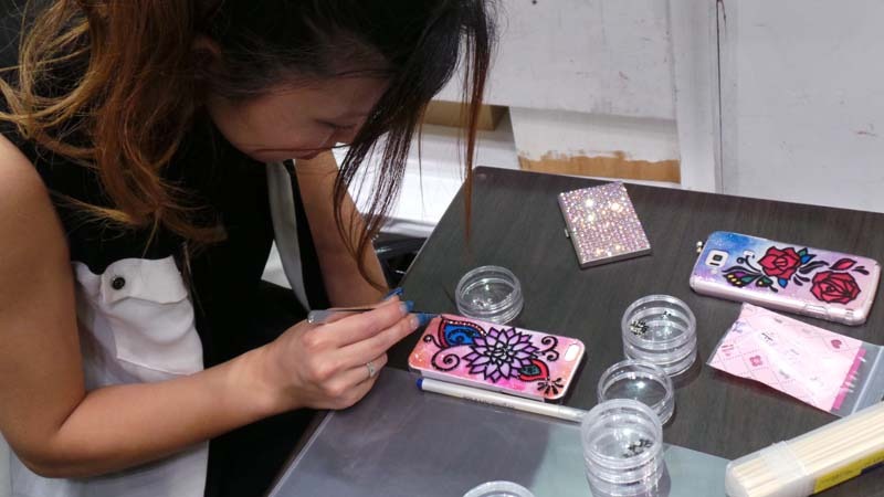 スマートフォンカバーにデコレーションを施すJeweluna・岡部真依氏
