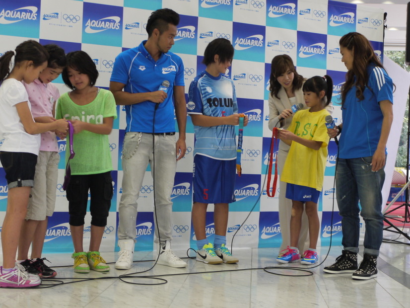 子供たちにメダルを見せる北島選手と澤選手