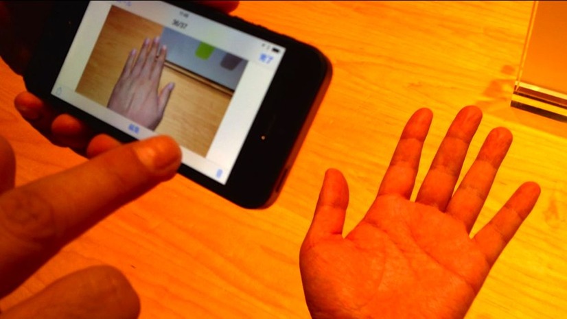 写真、電球色のライトのもとiPhone 5で撮影すると手がオレンジ色になってしまう。一方、iPhone 5sで撮影した画像を見ると自然な肌色となっている。