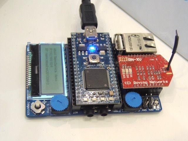 mbed（中央）とベースのアプリケーションボード。ベースボードには、LCD、LAN（イーサネット）、Wi-Fiモジュール、温度センサー、加速度センサー、アナログボリューム、ジョイスティック、オーディオ出力などを搭載