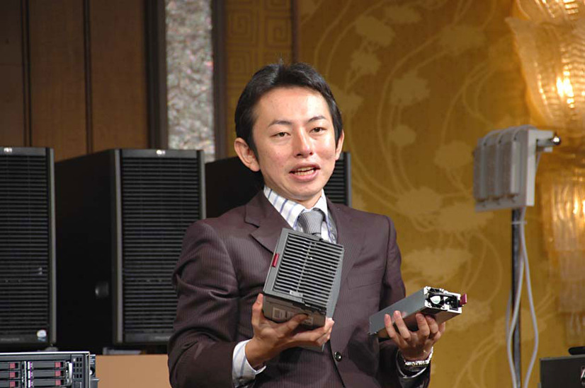 新開発の電源ユニットを見せる山中氏。向かって右の小さい方がが新しい100V電源