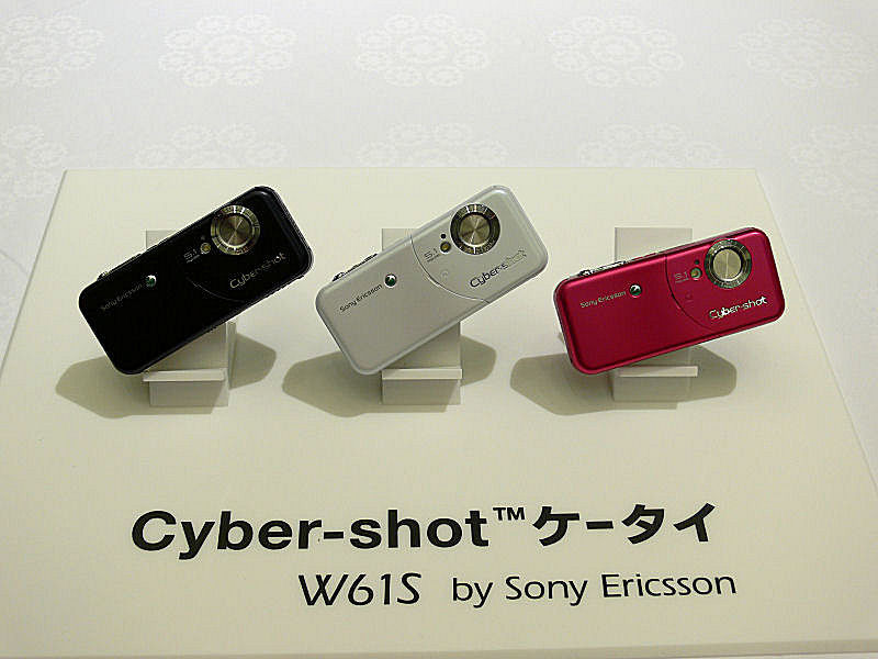 W61S。5メガピクセルカメラ＋スマイルシャッター Liteを搭載。本家Cyber-shotの同機能に比べると、笑顔認識速度が若干遅いこと、対象が3人までとなる。ISO1600対応、手ぶれ補正、Blogアップ機能などの搭載を予定する。実動機の展示はなかった