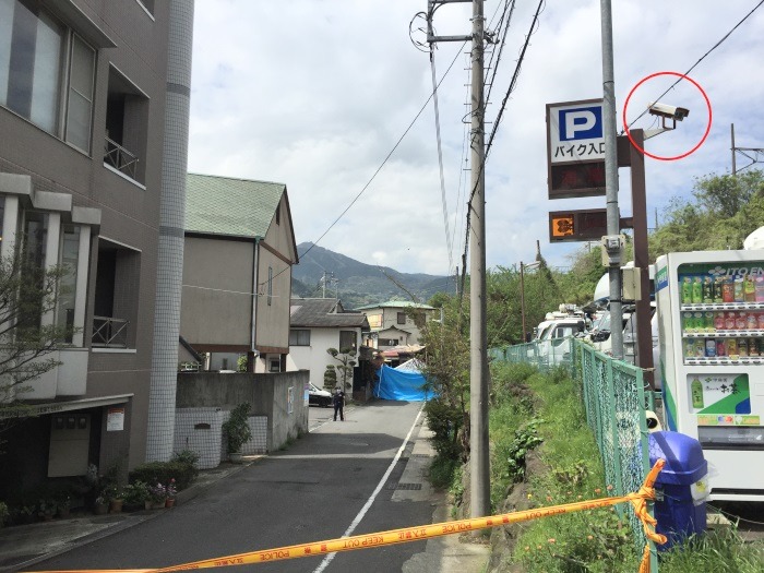 駅側から事件現場の方へと向かう小道には、駐車場の入退場を見る防犯カメラを確認できた