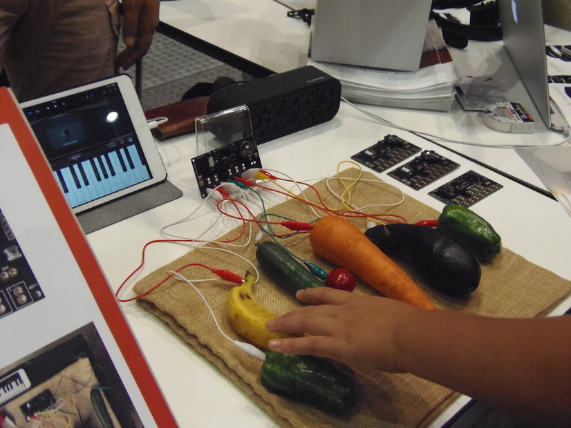 写真は、野菜や果物を使ってiPad用の楽器アプリを操作しているところ