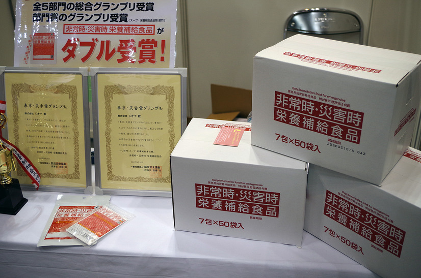 ジオナの「非常時・災害時栄養補給食品」はビタミンとミネラルを補給する備蓄用粉末食品。東京都の自治体や病院などでも備蓄品として採用されている。保存期間は5年間。一箱で50人/一週間分となっている（撮影：防犯システム取材班）