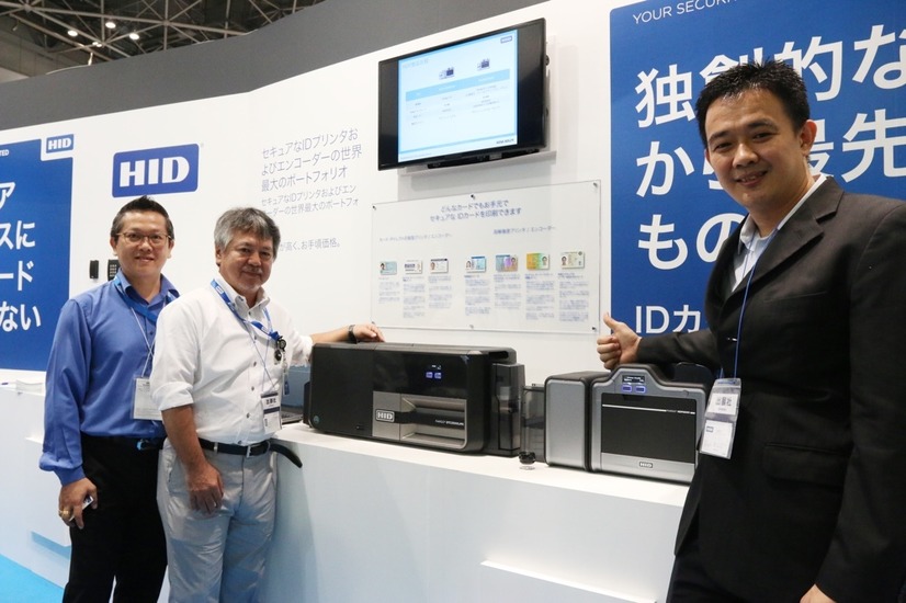 「FARGO（R）DTC5500LMX」と「FARGO（R）HDP5600」を前に詳細な説明してくれたHID Globalのセキュア・インシュアンス、アジア太平洋地域リージョナルディレクター　Wei Jin Lee／ウェイジン・リー氏（右）とHID Globalの面々（撮影：防犯システム取材班）