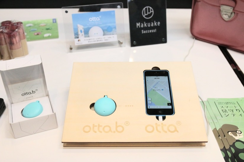 「otta」アプリと防犯ブザー型見守り端末「otta.b」のデモ展示。アプリを利用している“見守り人”によって取得された情報を元に保護者は子供の居場所を知ることができるサービスとなる（撮影：防犯システム取材班）