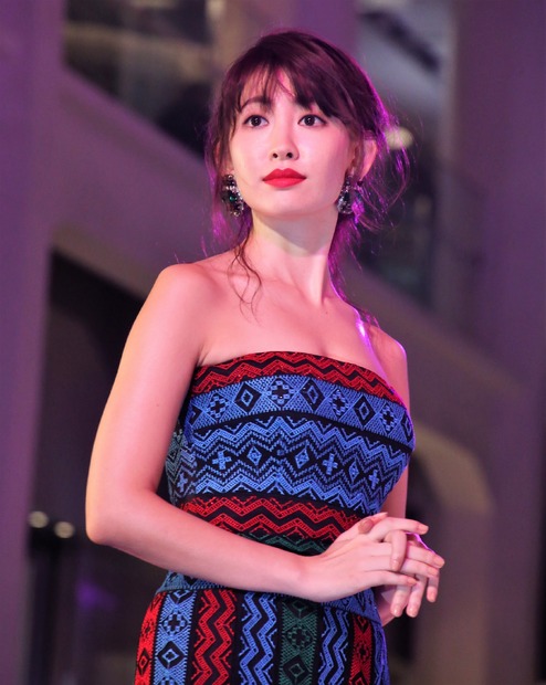 背中まで見せつける大胆なドレスで登場