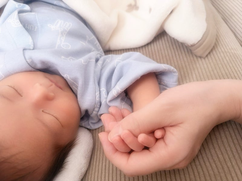 眠っている息子と手をつないでいる写真（写真は小松彩夏の公式ブログから）