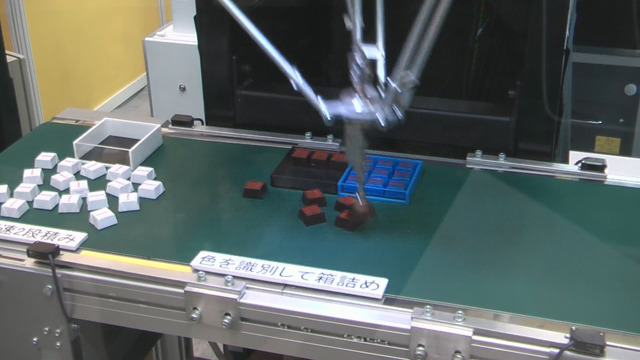 ファナックの「ゲンコツ・ロボット1号」によるデモ。高速に文房具やチョコレートを収納していく。色や形も識別する。