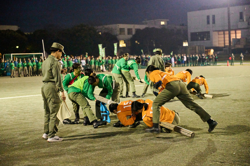 棒を敵陣に運ばれまいと棒にしがみつき、一方、棒を自陣に運び込もうと力の限り棒を引っ張る女子学生たち