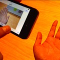 写真、電球色のライトのもとiPhone 5で撮影すると手がオレンジ色になってしまう。一方、iPhone 5sで撮影した画像を見ると自然な肌色となっている。