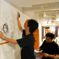 サインを壁に描く会田氏。