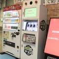 ダイドードリンコのブースに設置されていた小型監視カメラシステム「Dec On Camera」を搭載した自販機。本ブースでは防災情報を提供するサイネージと組み合わせた自販機なども展示されていた（撮影：編集部）