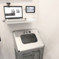 「防犯機能付ダストボックス」のシステム全景。床には圧電マットが敷かれており、踏まれることで発電し、ゴミ箱内部のカメラを作動させる（撮影：防犯システム取材班）