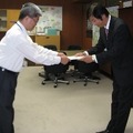 高崎一郎 総務省 四国総合通信局長（左）から免許状を受領する片岡浩一 UQコミュニケーションズ 副社長（右）