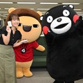 お互いの名刺を持つ山崎香佳アナウンサー(左)とくまモン(右)、おとなしく待機するらいよんチャン(中央)©2010 熊本県くまモン©MBS