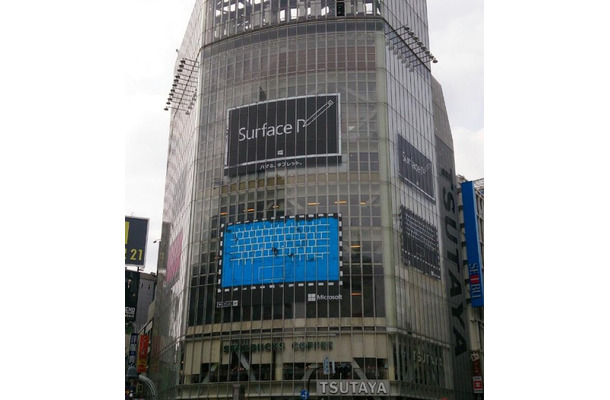 「QFRONT」の壁面に掲示された、「Surface」にペンで「P」という文字を書きかけた広告