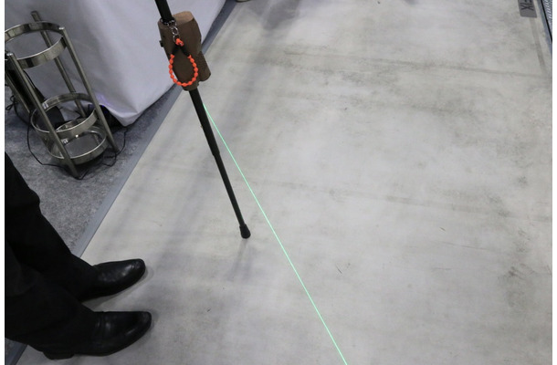 レーザー光を照射する筐体を装着した杖となっており、杖をつくと踏み出し線が照射される（撮影：防犯システムNAVI）